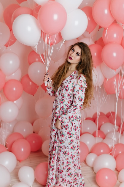 Belle jeune fille vêtue d'une robe parmi beaucoup de boules roses.