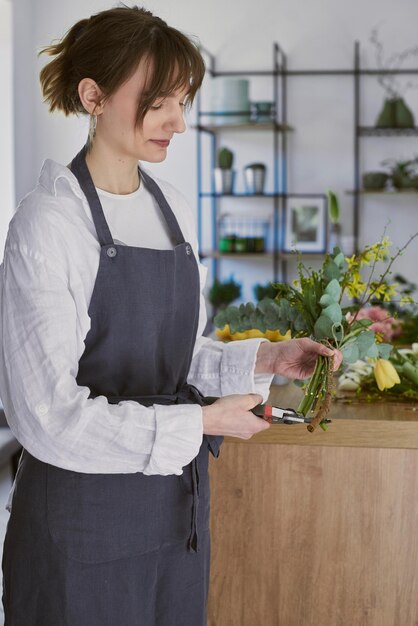 Belle jeune fleuriste fait un bouquet