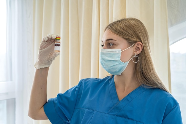 Belle jeune infirmière en uniforme et gants tenant un vaccin Concept de médecine Concept de vaccination Concept Covid