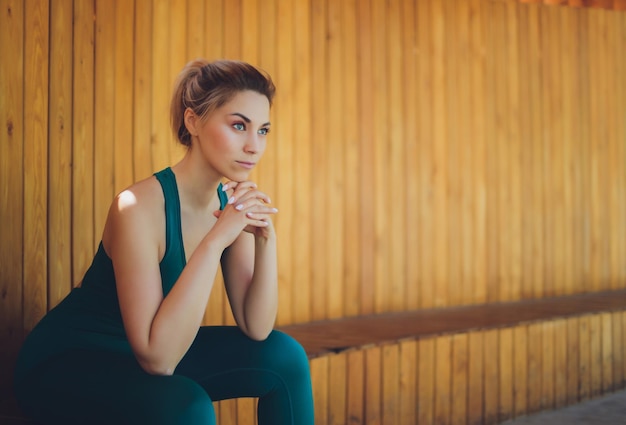 Belle jeune instructeur de fitness donne des cours en vidéo à l'aide d'un ordinateur portable sur une véranda en bois dans la rue