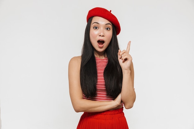 belle jeune jolie femme asiatique choquée posant isolée sur un mur blanc pointant avoir une idée.