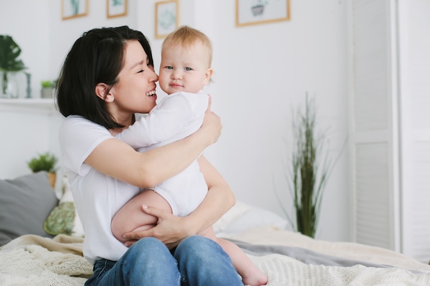 Belle jeune maman asiatique heureuse câlins sa petite fille dans la chambre