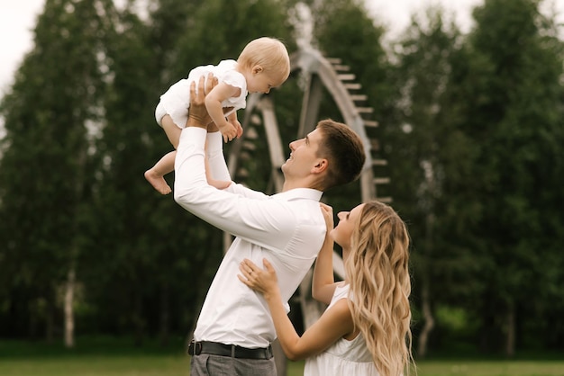 Belle jeune maman et papa de famille avec une fille d'un an dans la famille heureuse de la nature