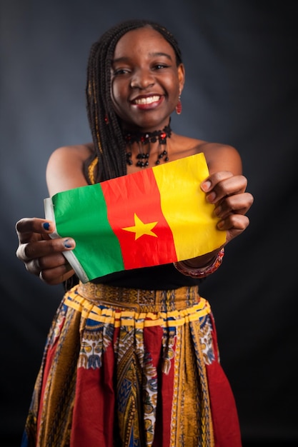 Belle jeune mannequin africaine avec le drapeau du Cameroun en costume traditionnel