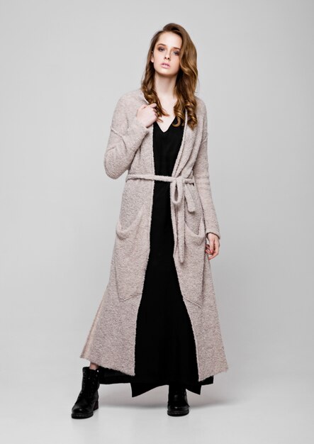 Belle jeune mannequin portant une robe en tricot sur gris