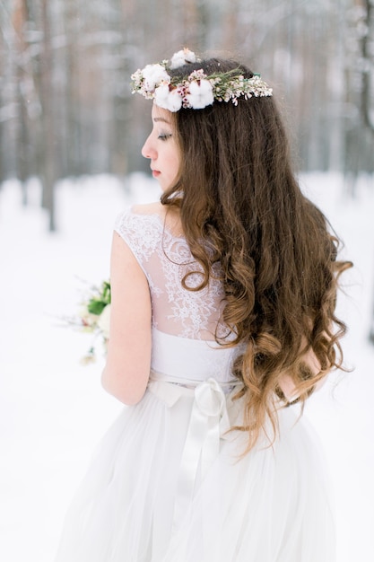 Belle jeune mariée dans la forêt enneigée d'hiver