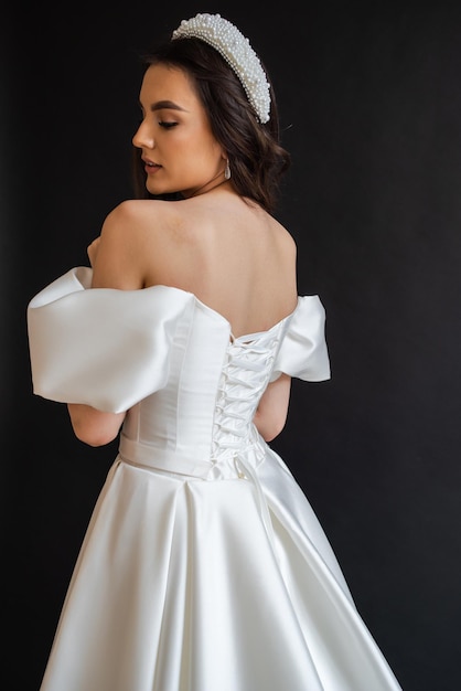 Belle jeune mariée modèle sexy aux cheveux noirs dans une magnifique robe de mariée longue et brillante