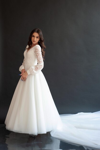 Belle jeune mariée modèle sexy aux cheveux noirs dans une magnifique robe de mariée longue et brillante