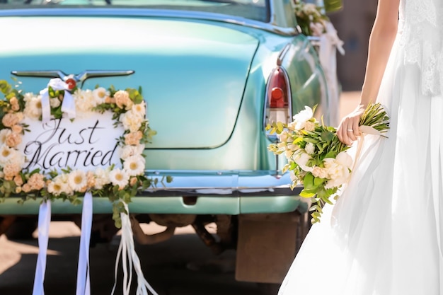 Photo belle jeune mariée près d'une voiture décorée