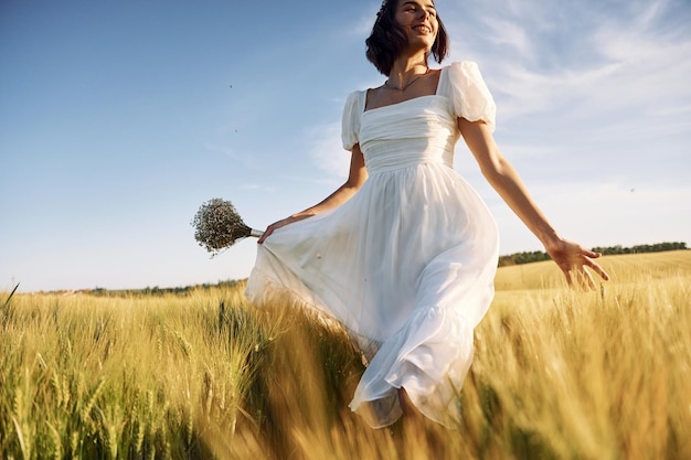 Belle jeune mariée en robe blanche est sur le terrain agricole aux beaux jours