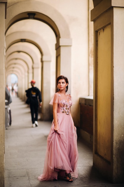 Une belle jeune mariée se dresse au centre de la vieille ville de Florence en Italie. Mariée dans une belle robe rose en Toscane.Italie