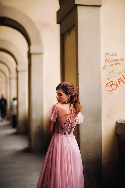 Une belle jeune mariée se dresse au centre de la vieille ville de Florence en Italie. Mariée dans une belle robe rose en Toscane.Italie