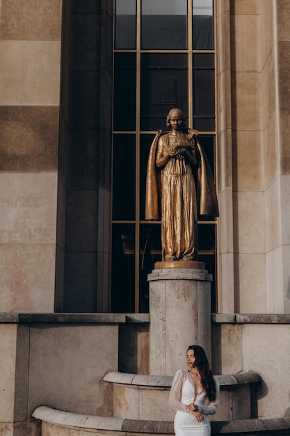 La belle jeune mariée se tient devant les statues