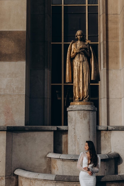 La belle jeune mariée se tient devant les statues