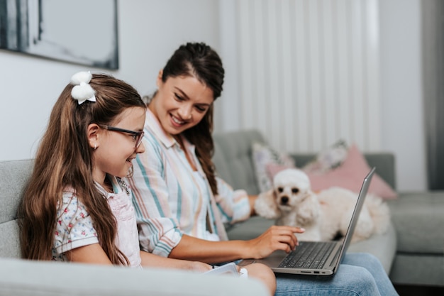 Belle jeune mère aidant sa fille cadette à faire ses devoirs.