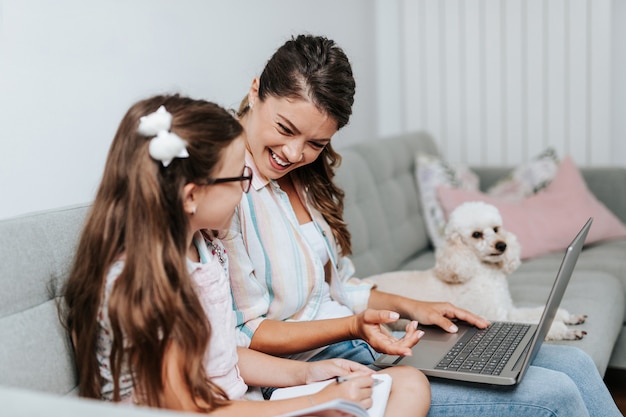 Belle jeune mère aidant sa fille cadette à faire ses devoirs.