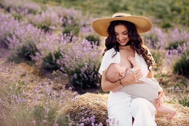 Belle jeune mère allaitant son bébé dans un champ de lavande