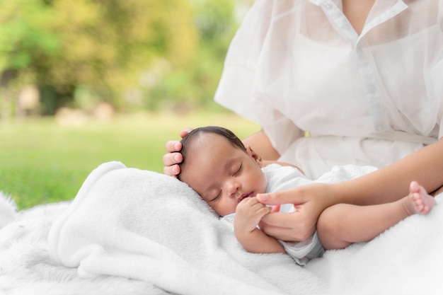 Belle jeune mère asiatique tenant son nouveau-né dort et se sent avec amour