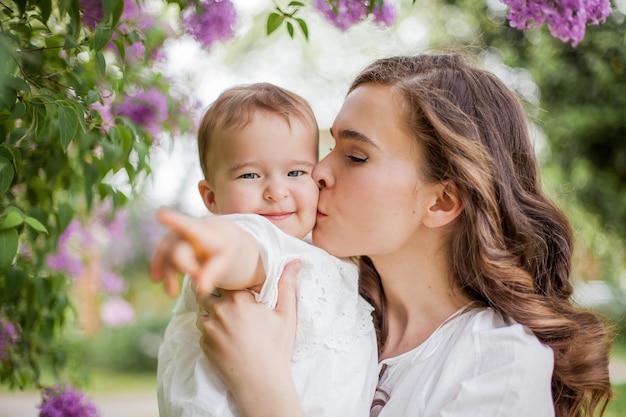 Belle jeune mère et fille près du lilas en fleurs. Printemps.