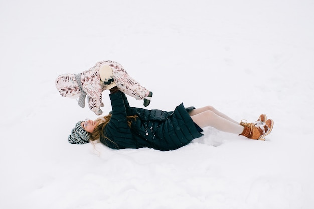 Belle jeune mère jouant avec petite fille en plein air en hiver.