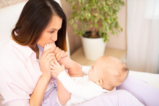 Une belle jeune mère joue et câline avec son bébé sur le lit Amour maternité