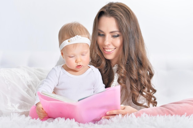 Belle jeune mère avec sa fille lisant un livre