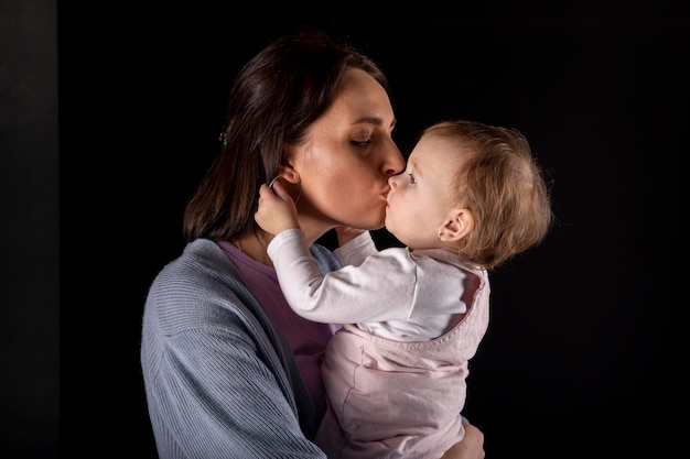 Belle jeune mère avec sa fille mignonne et heureuse sur fond noir.