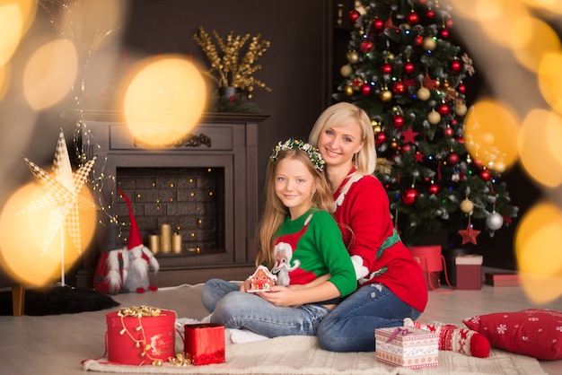 Belle jeune mère avec sa fille près de l'arbre de Noël