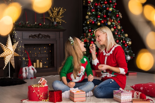 Belle jeune mère avec sa fille près de l'arbre de Noël