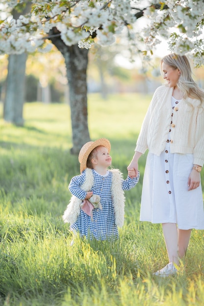 Une belle jeune mère avec sa petite fille se repose sur un pique-nique dans le jardin fleuri