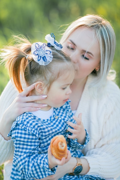 Une belle jeune mère avec sa petite fille se repose sur un pique-nique dans le jardin fleuri