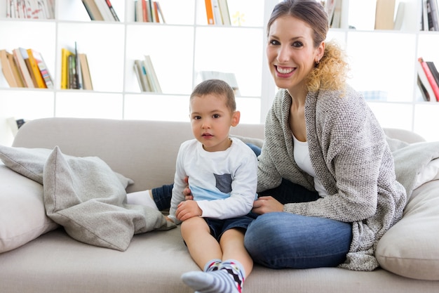 Belle jeune mère et son fils regardant la caméra à la maison.