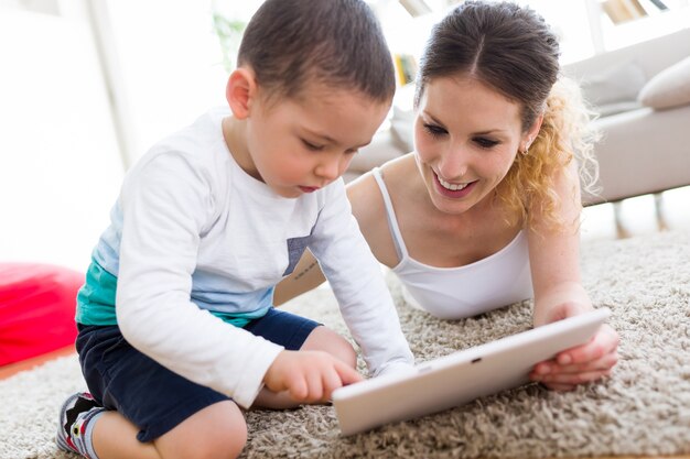 Belle jeune mère et son fils utilisant la tablette numérique à la maison.