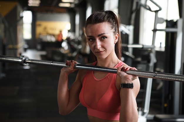 Belle jeune sportive faisant des exercices de presse poussée avec haltères