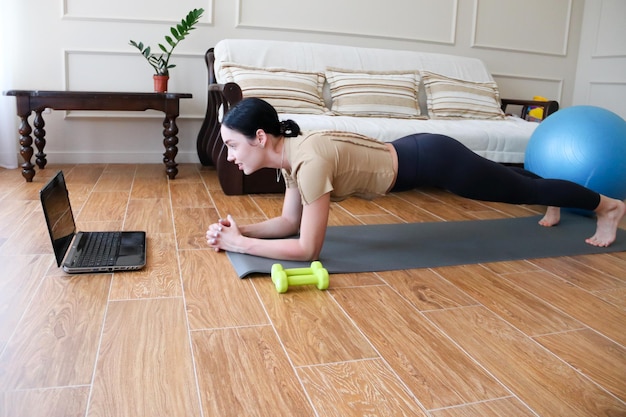 Une belle jeune sportive en leggings et un haut fait du sport à la maisonSports en ligne à la maison