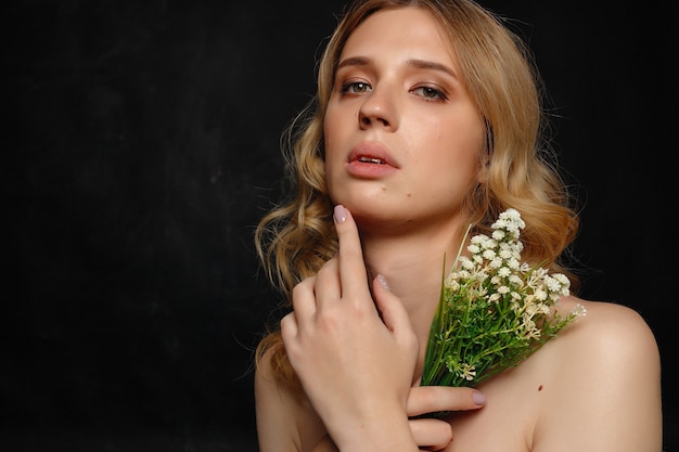 Belle jeune transgenre aux cheveux blonds tenant des fleurs