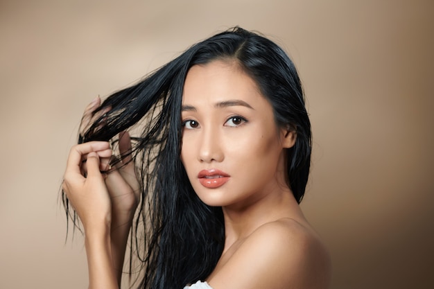 Belle jolie femme asiatique élégante main toucher visage modèle pose sur fond blanc isolé photoshoot studio