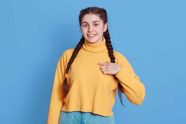 Belle jolie femme brune souriante et pointant avec l'index sur elle-même, vêtue d'un pull à manches longues