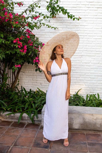 Belle jolie femme élégante en robe blanche et chapeau de paille par nature tropicale