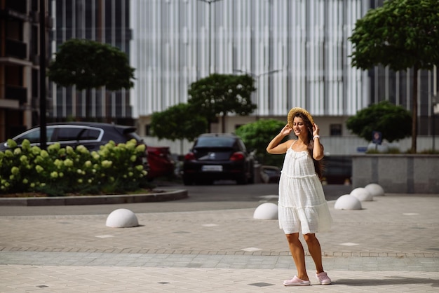 Belle jolie femme en robe blanche marchant dans la rue de la ville