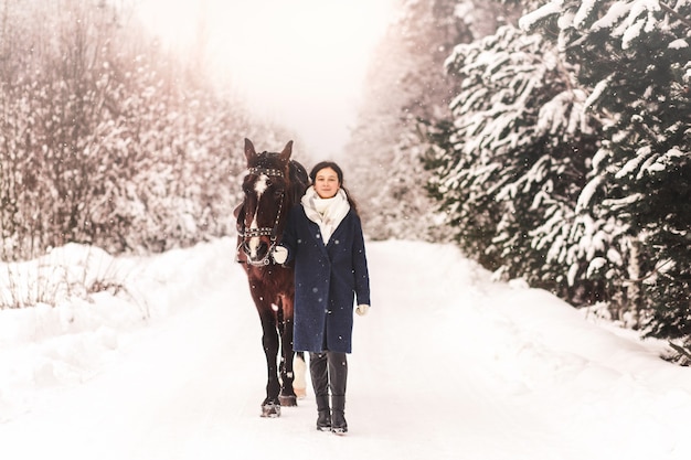 Belle jolie fille va avec un cheval dans les bois en hiver