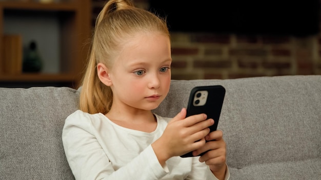 Belle jolie petite fille élève caucasien enfant fille blogueuse s'asseoir sur un canapé à la maison