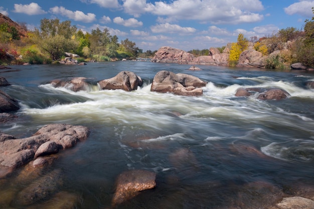 Belle journée d'automne ensoleillée sur la rivière avec cascade et gros rochers
