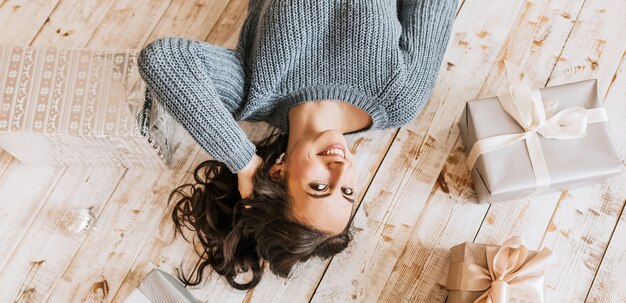 Belle joyeuse jeune fille heureuse avec des jouets de Noël et des cadeaux sur le plancher en bois