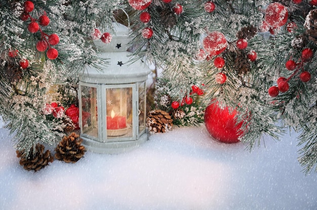 Belle lanterne de Noël avec des bougies et des branches de sapin avec des cônes et des baies rouges