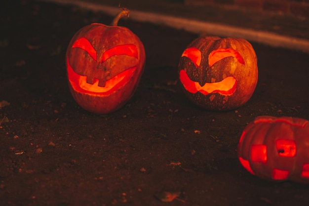 Belle lueur souriante orange drôle de visage citrouilles sculptées pour les vacances d'Halloween la nuit en plein air