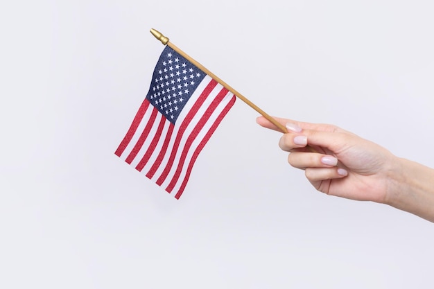 Une belle main femelle tient un drapeau américain sur un fond blanc