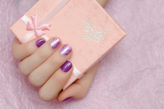 Belle main féminine avec nail art violet.