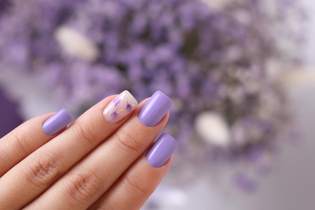 Belle main féminine avec ongles de manucure pourpre design de fleurs