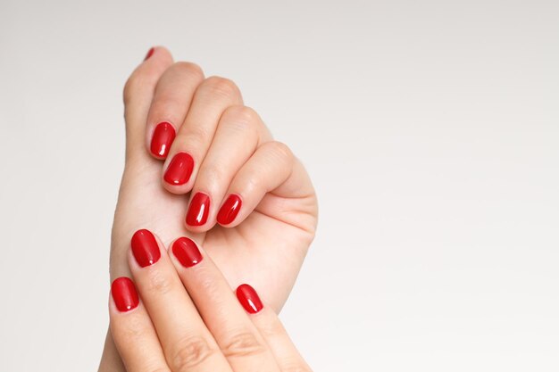 Belle main féminine peignant des ongles rouges en gel acrylique style de mode